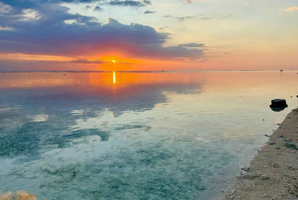 Tramonto balinese su laguna trasparente con riflessi rosa e turchese